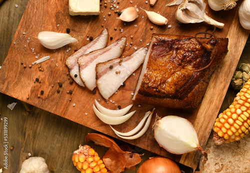 still life of food in a rural style on a dark wood background, sliced lard and garlic, cheese, corn and onion, concept of fresh vegetables and healthy food