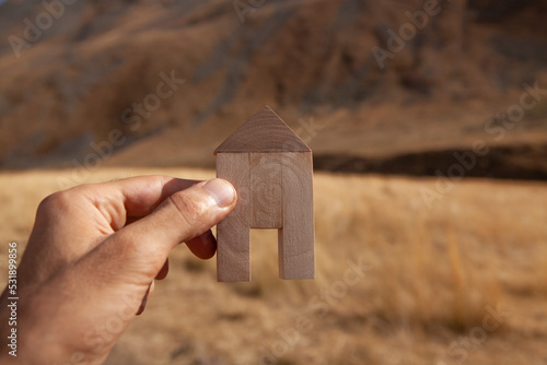 holding a house in his hand on the background of nature