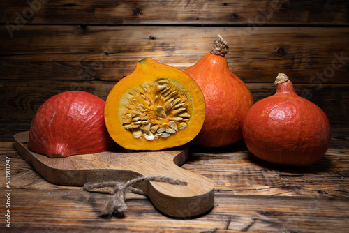 Hokkaido pumpkins on wooden background. Red kuri squash autumn fall rustic composition for Halloween or Thanksgiving. photo