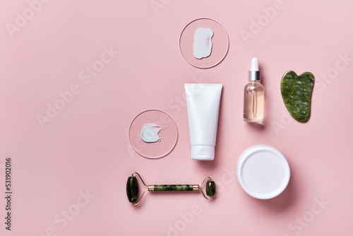 Cosmetic beauty products and stone massagers on pink background. Face massage skincare concept