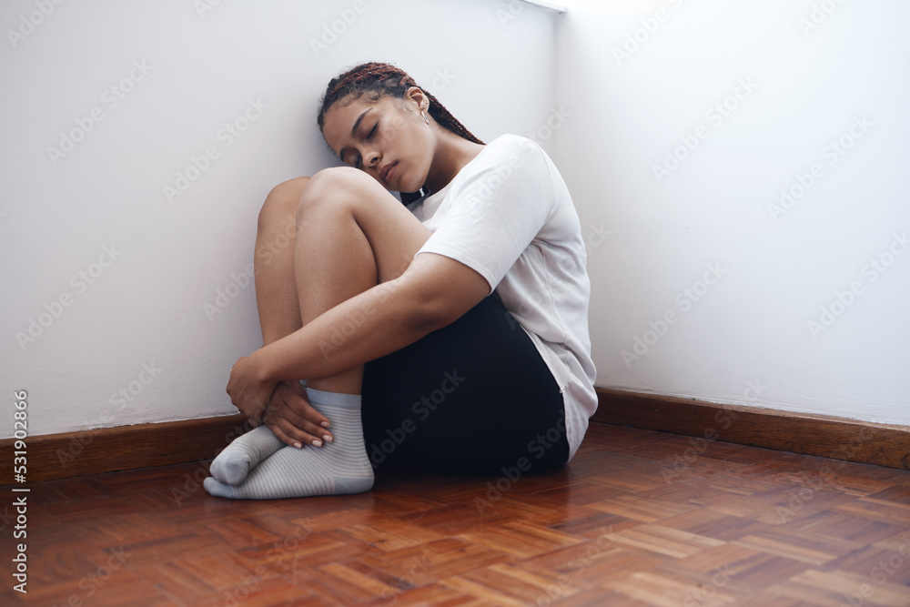 Depression, anxiety and lonely woman sitting in a corner suffering from mental health issues or problems. Black female in stress, depressed or abuse alone on a wooden floor in apartment, home or room Depression, anxiety and lonely woman sitting in a corner suffering from mental health issues or problems. Black female in stress, depressed or abuse alone on a wooden floor in apartment, home or room