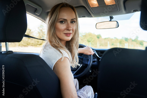 Caucasian blonde woman sitting in car and turning to camera © gpointstudio