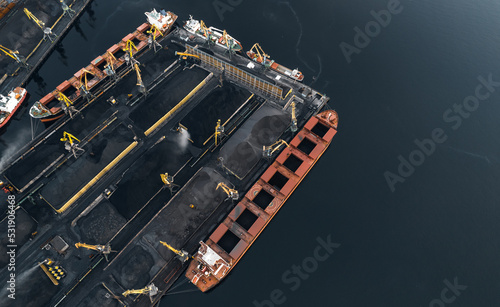 Loading coal anthracite mining in port on cargo tanker ship with crane bucket of train. Aerial top view photo