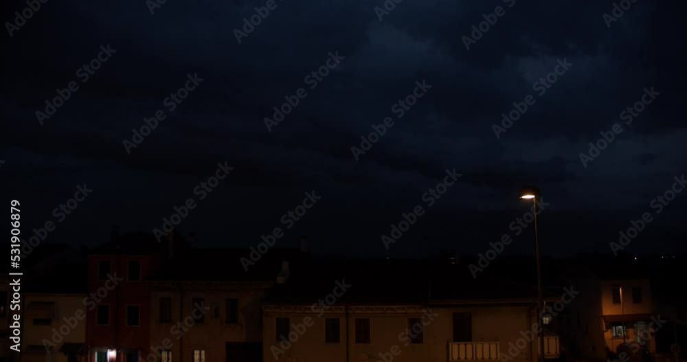 Intense thunderstorm with lightning in the clouds above roofs of houses. Night sky just after a strong summer storm in Italy. Natural disasters and climate change. Intense thunderstorm with lightning in the clouds above roofs of houses. Night sky just after a strong summer storm in Italy. Natural disasters and climate change.
