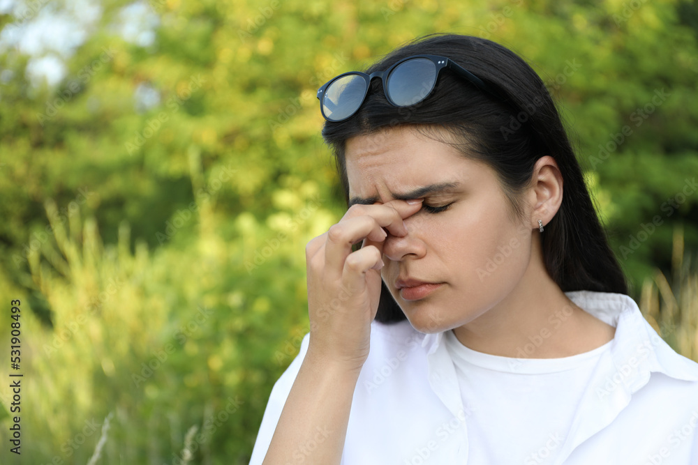 Young woman suffering from eyestrain outdoors on sunny day Young woman suffering from eyestrain outdoors on sunny day