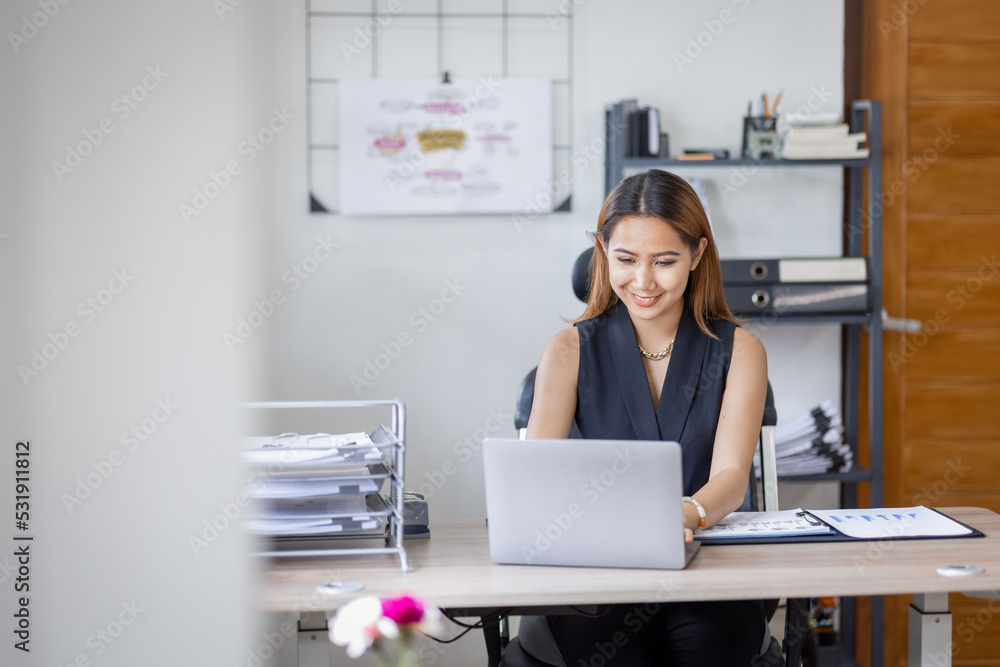Young Asian female freelancer employee working at home workplace with laptop and papers on desk Young Asian female freelancer employee working at home workplace with laptop and papers on desk