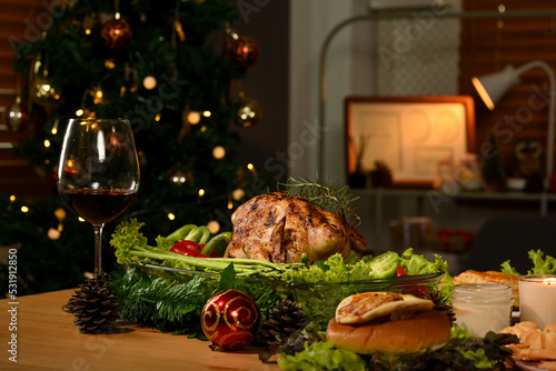 Thanksgiving table with roasted turkey  red wine and sides dishes in decorated room with a Christmas tree