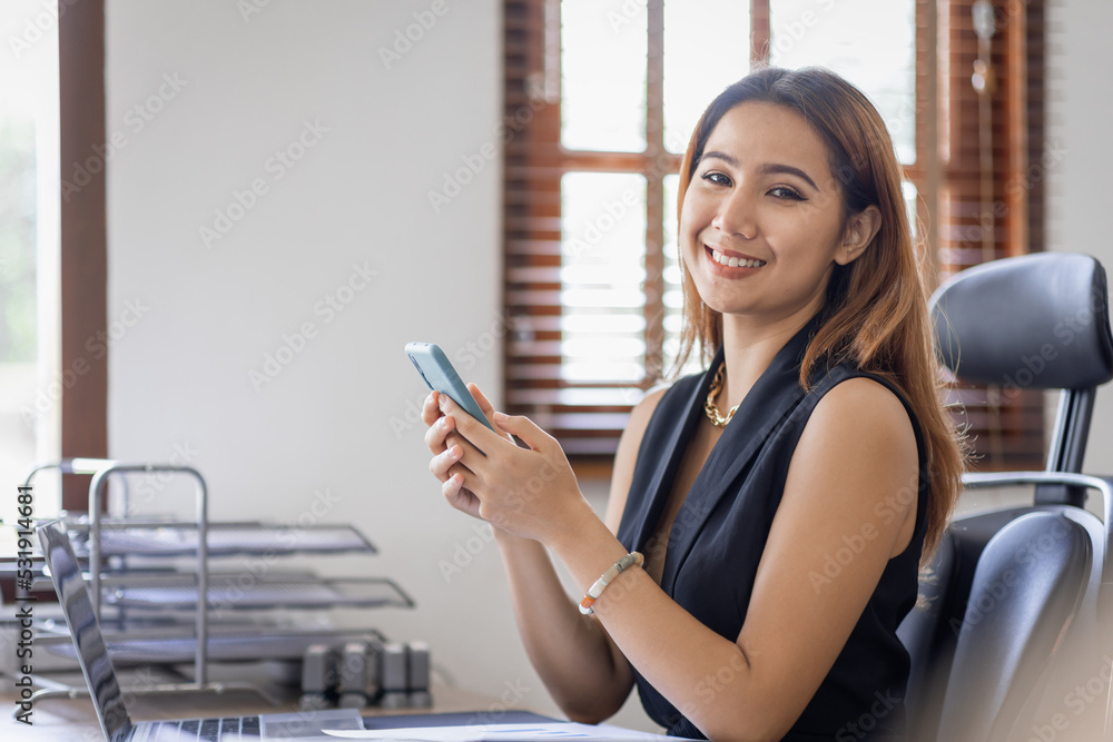 Happy Excited Asian young entrepreneur business woman using phone and laptop sitting on a desk at home workplace,