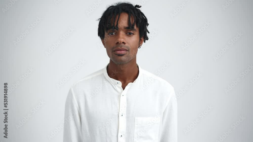 Confident African man with dreadlocks opening eyes at the camera in the white studio Confident African man with dreadlocks opening eyes at the camera in the white studio