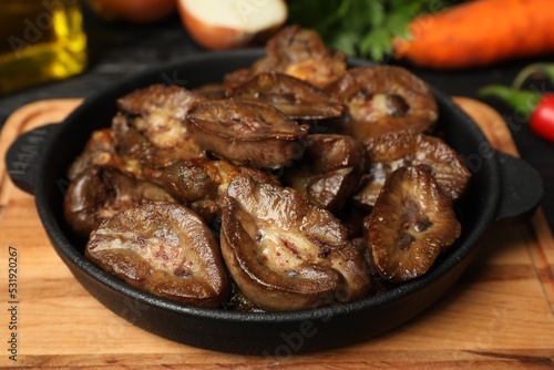 Frying pan with delicious kidneys on wooden board, closeup