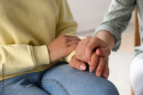 Psychotherapist holding patient's hand in office, closeup