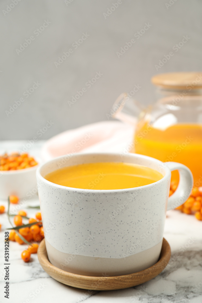 Delicious sea buckthorn tea on white marble table Delicious sea buckthorn tea on white marble table