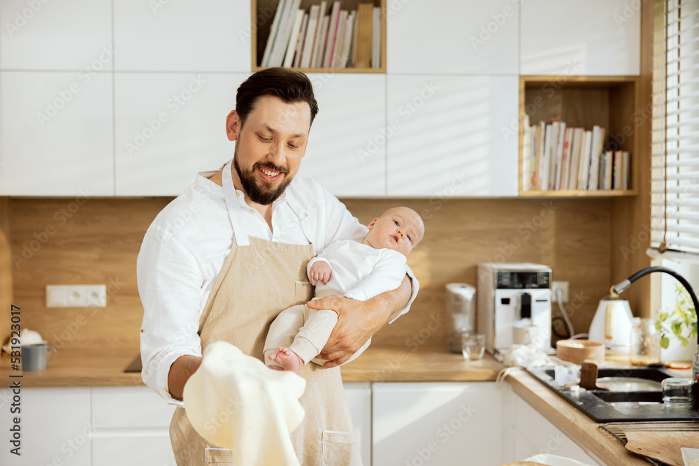Adorable son in father's hand resting. Man kneading rolling throwing up homemade dough smiling. Preparing surprise for family dinner baking pizza.