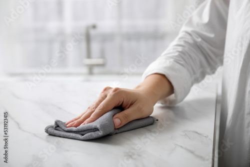 Woman wiping white marble table indoors, closeup © New Africa