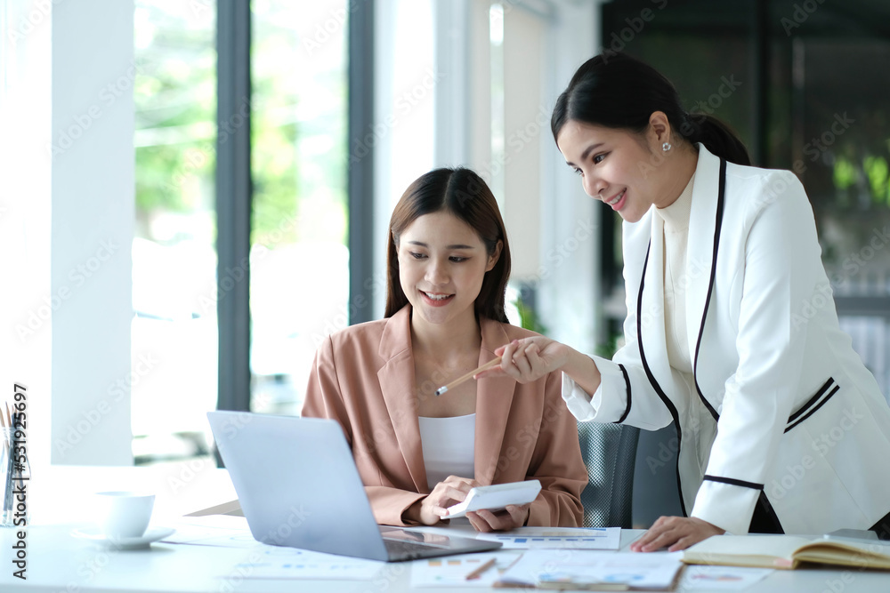 Two young Asian business woman talk, consult, discuss working with new startup project idea presentation analyze plan marketing and investment in the office. Two young Asian business woman talk, consult, discuss working with new startup project idea presentation analyze plan marketing and investment in the office.