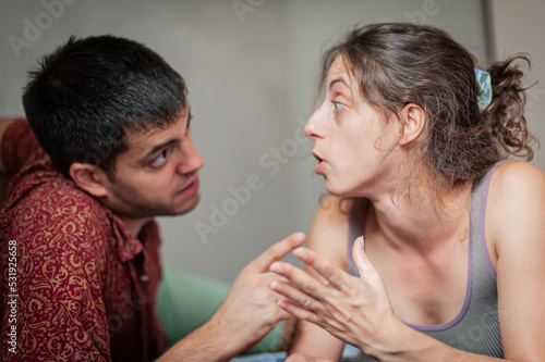 A man and a woman are arguing on the bed in the apartment. They are in a bad mood because they have love problems.
