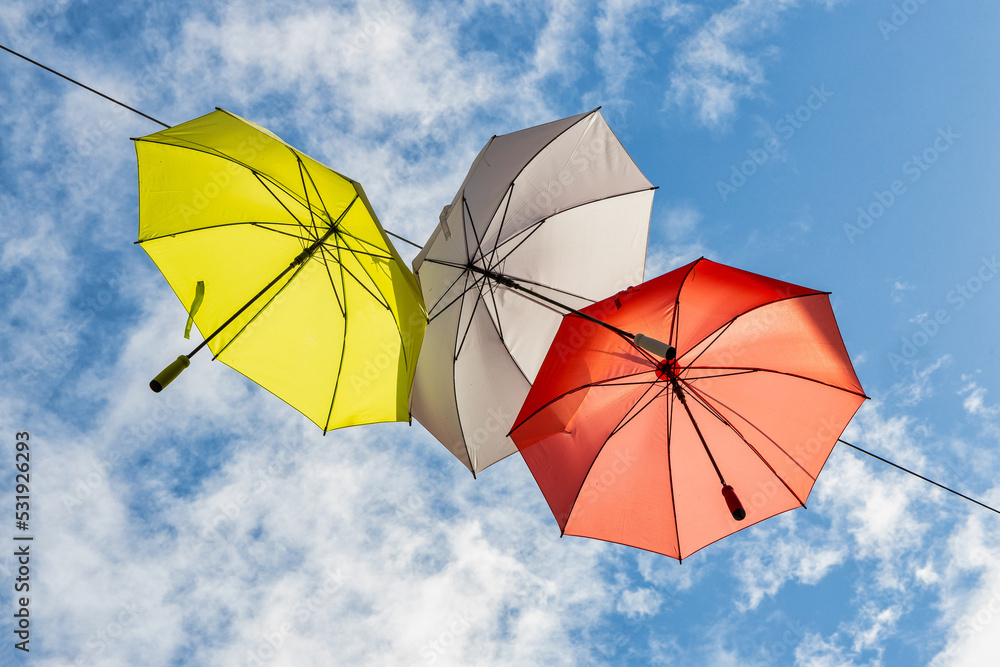 Colorful umbrellas in the air against blue sky with clouds