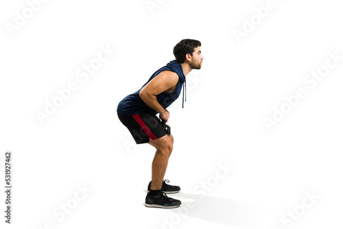 Active hispanic man doing a squat with a kettlebell weight
