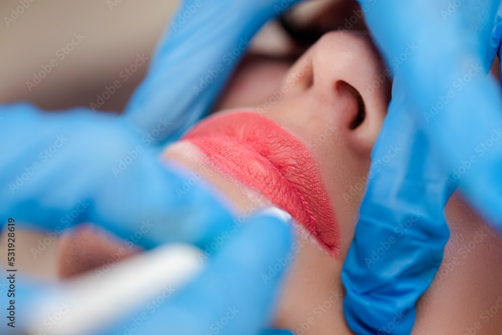 Fototapeta premium Young woman undergoing procedure of permanent lip makeup in tattoo salon, closeup