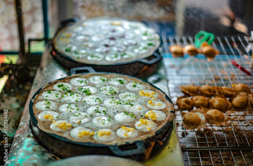 A vendor is making khom krok in a pit tray to sell in the fresh seafood market of Ban Na Kluea, Pattaya, Thailand.