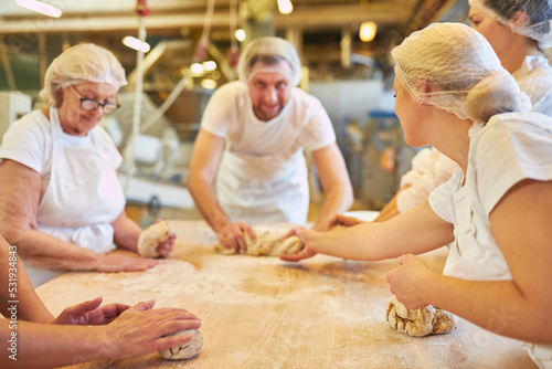 Baker team with apprentices kneading the dough