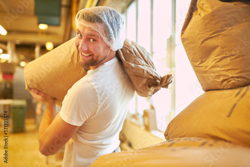 Baker or miller carries large sack of flour to the bakery photo