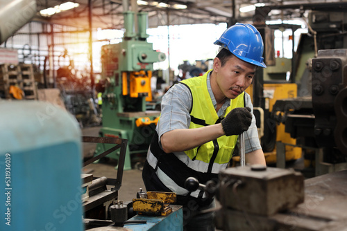 Technician engineer or worker in protective uniform standing and repairing operation or checking industry machine process with safety hardhat at heavy industry manufacturing factory