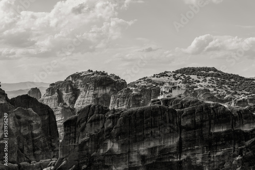Black and white shot of pillar-like cliffs and mountain range with 2 biggest monasteries of Varlaam and Great Meteoron, Greece.