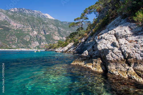Obraz na płótnie Beautiful landscape on the sea, the rocky coast, view on the mountains and small boat with people. Blue lagoon in Oludeniz, Turkey. Small boats on clear water. Tourism. w salonie