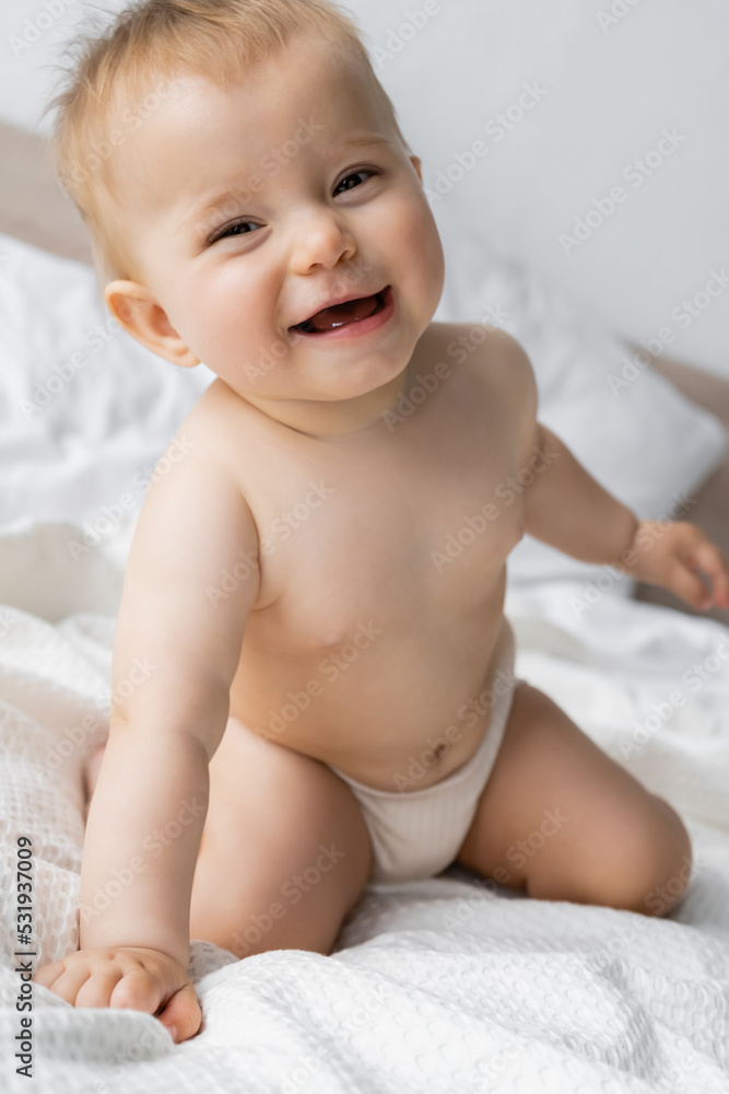 Infant girl in panties smiling at camera while sitting on bed. Infant girl in panties smiling at camera while sitting on bed.