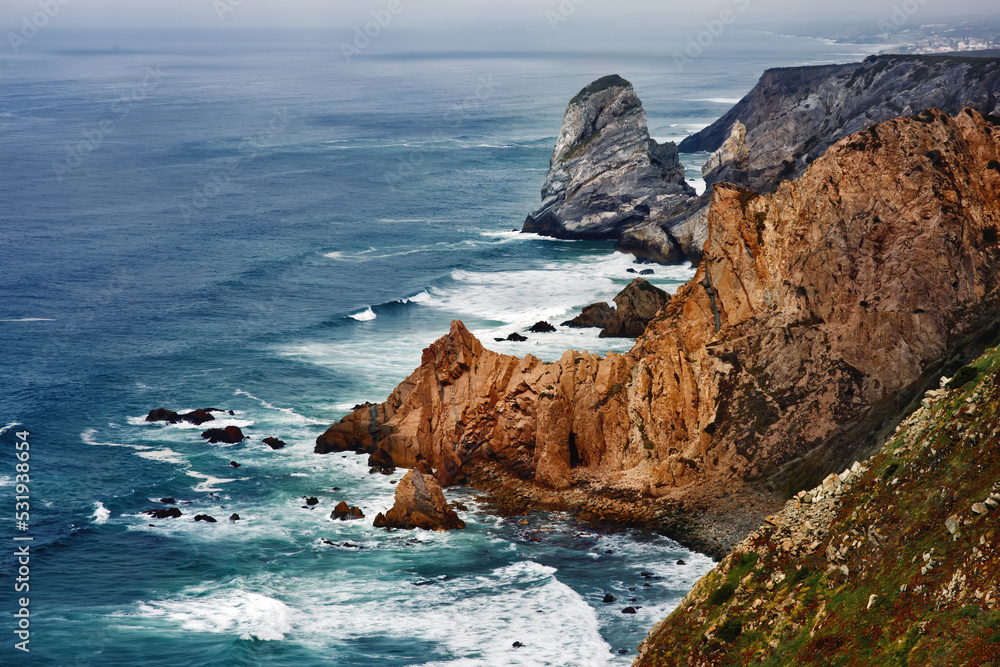Picturesque view of coastline of Atlantic ocean with cliffs, rocks, waves, splashing, wind in Cape Rock, Portugal, the most western point of Europe, famous place for traveling, background Picturesque view of coastline of Atlantic ocean with cliffs, rocks, waves, splashing, wind in Cape Rock, Portugal, the most western point of Europe, famous place for traveling, background