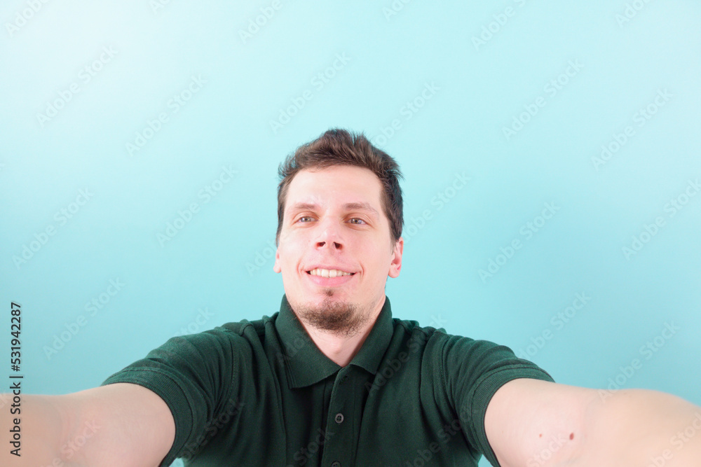 Fototapeta premium Black hair man taking two hands selfie and smiling on a blue background. Foolish. Career. Fashionable. Enjoy. Excited. Individual. Journey. Hipster. Laughing. Kind. Model. Happiness. Smiling