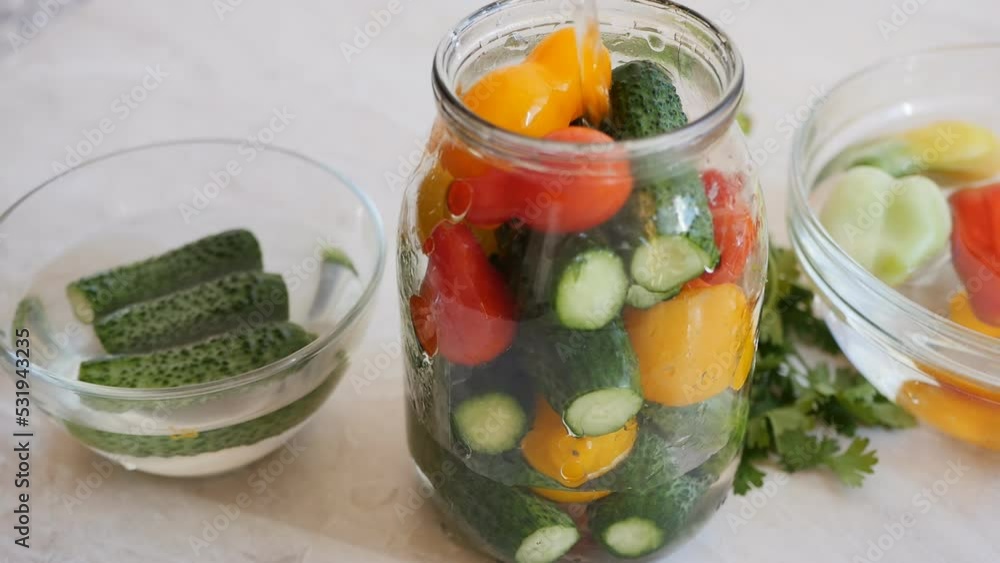 Pour the salt solution into a jar of yellow and red cucumbers and tomatoes for long-term preservation in the marinade and eating on any day. Organic long shelf life food. Proper nutrition Pour the salt solution into a jar of yellow and red cucumbers and tomatoes for long-term preservation in the marinade and eating on any day. Organic long shelf life food. Proper nutrition