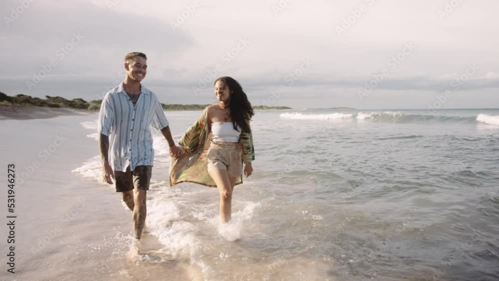 Affectionate young couple holding hands while dancing in sea Affectionate young couple holding hands while dancing in sea