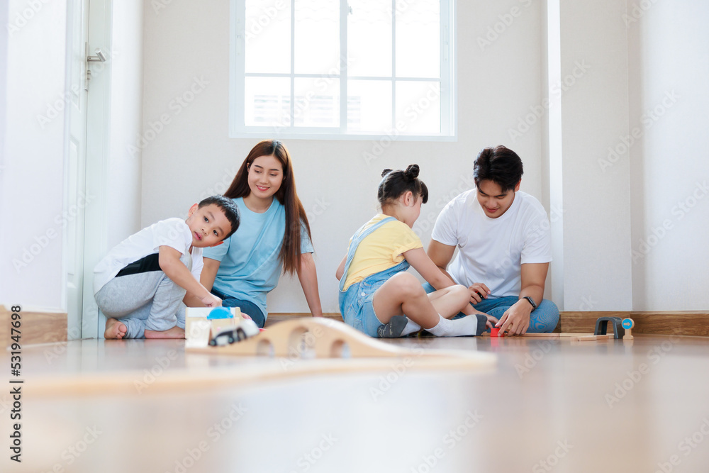 Happy asian family playing wood block create rail road together at home Happy asian family playing wood block create rail road together at home
