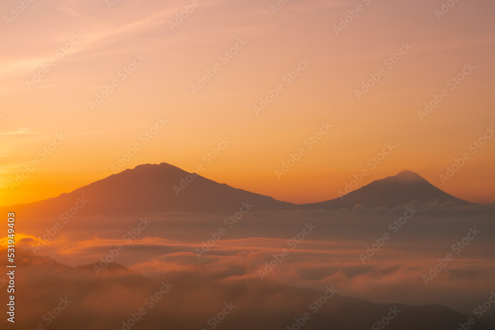 Golden sunrise over white puffy clouds with distant mountains on horizon Golden sunrise over white puffy clouds with distant mountains on horizon
