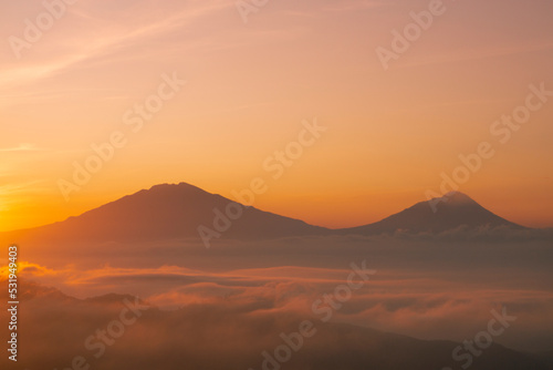 Golden sunrise over white puffy clouds with distant mountains on horizon