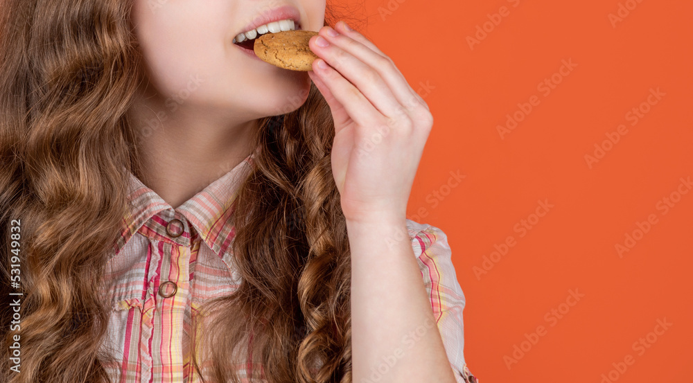 cropped view of girl eating oatmeal cookies on orange background. copy space