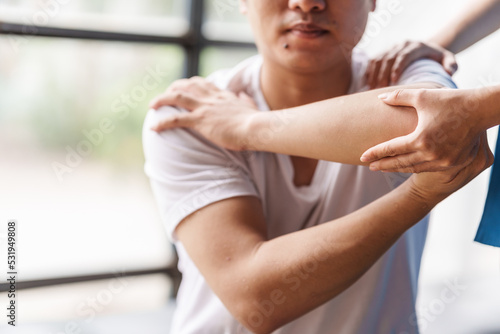 Physical therapist is examining the injured arm, waist and neck muscles of an athletic male patient.