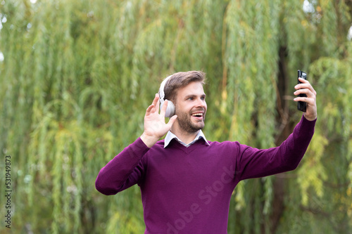 young handsome man listen music and blogging on phone outdoor