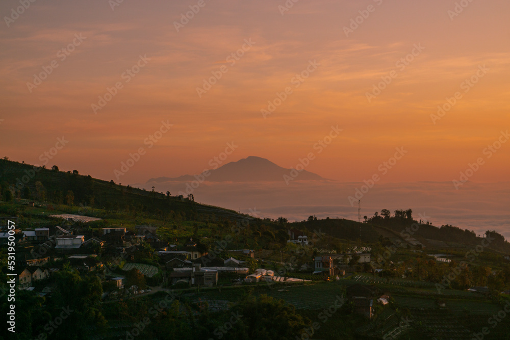 Sunrise over mountain with view of village on the slope of Mountain. Mangli Village on the slope of Sumbing Mountain