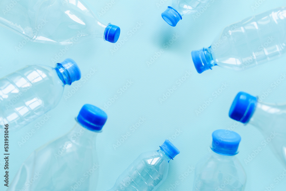 Plastic used bottles on a blue background. There is empty space in the center. The concept of consumerism and pollution of nature with plastic waste. Selective focus on background Plastic used bottles on a blue background. There is empty space in the center. The concept of consumerism and pollution of nature with plastic waste. Selective focus on background