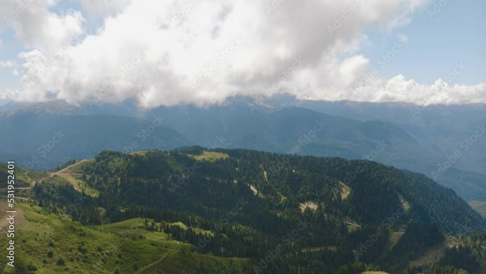 White clouds fly over the green hills. Mountain landscape. Forest on the slopes of the hills. Paths. Drone 4k footage White clouds fly over the green hills. Mountain landscape. Forest on the slopes of the hills. Paths. Drone 4k footage