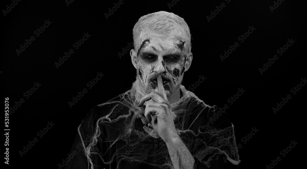 Shh be quiet. Sinister man with horrible scary Halloween zombie makeup
