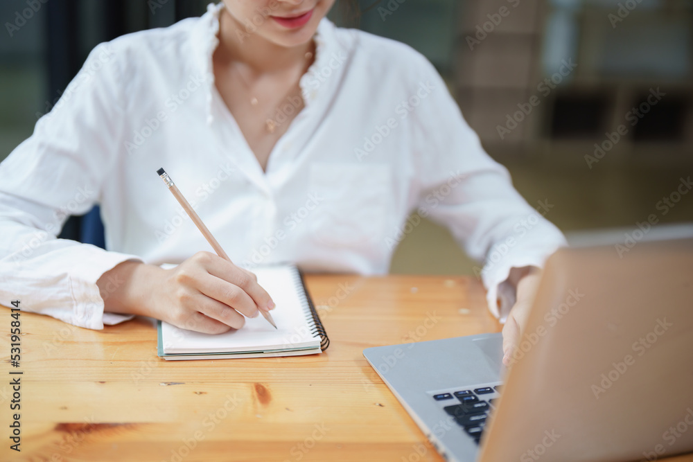 woman using a notebook and computer during a video conference woman using a notebook and computer during a video conference