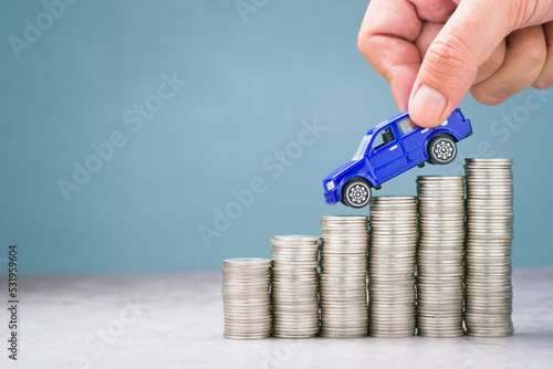 Fototapeta Hand pick the toy car driving down on the descending money, more savings for buy