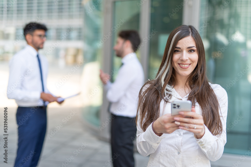 Businesswoman using her smartphone in front of her office Businesswoman using her smartphone in front of her office