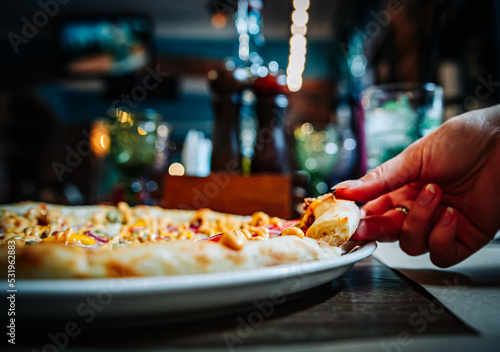 Fototapeta Naklejka Na Ścianę i Meble -  woman Hand takes a slice of meat Pizza with Mozzarella cheese, salami, Tomatoes, pepper, ham in cafe
