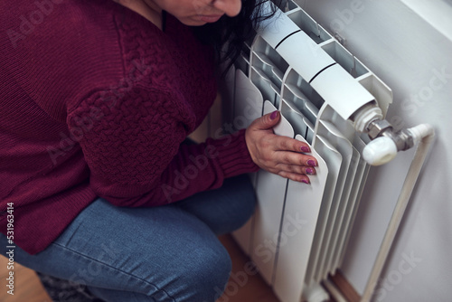 Woman heating on a chilly winter day, energy and gas crisis, cold room, heating problems.