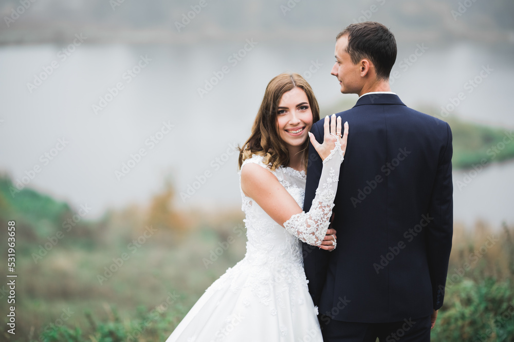 Beautiful romantic wedding couple of newlyweds hugging in park